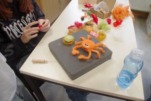 Tisch auf dem verschiedenfarbige Filzstücke liegen und eine rosa Filz-Krabbe